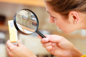 Mature woman female inspecting testing butter food label with magnifying glass.